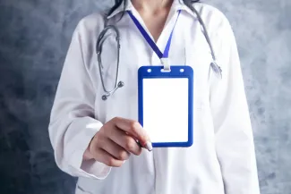 person in white and blue medical scrub holding blue and white card by Sasun Bughdaryan courtesy of Unsplash.